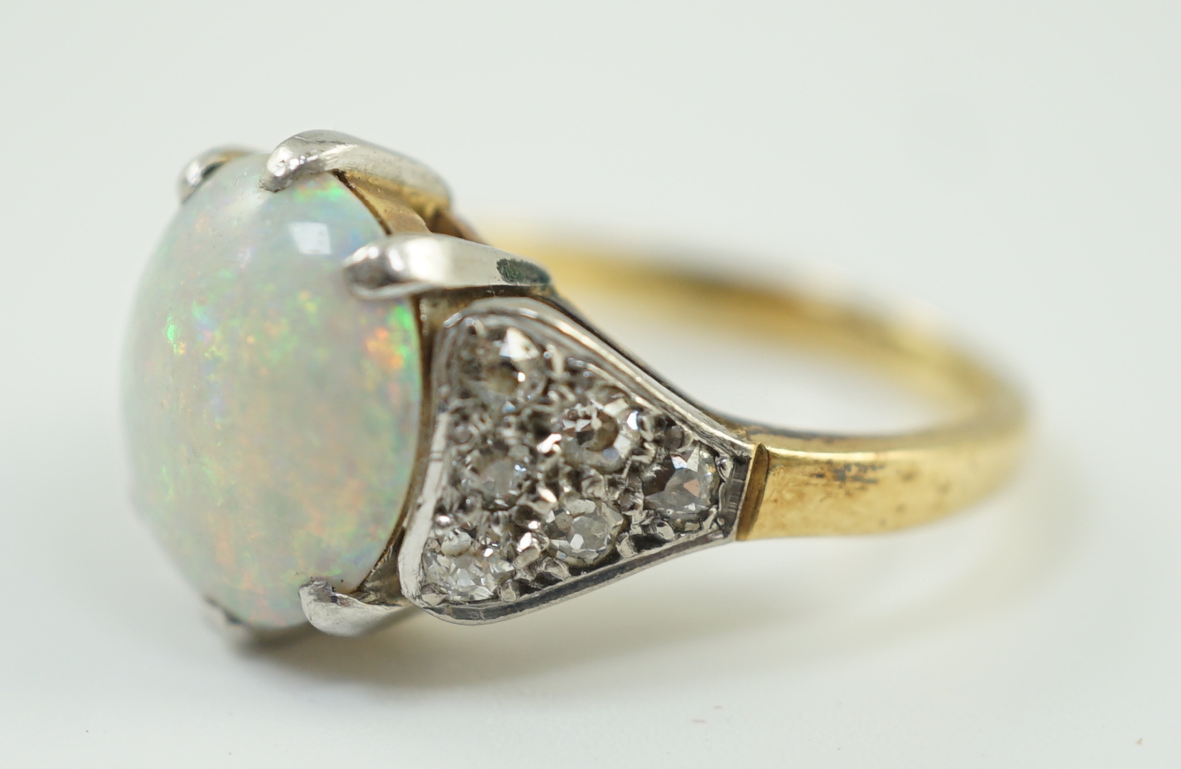 An 18ct gold and single stone white opal set ring, with twelve stone diamond set shoulders